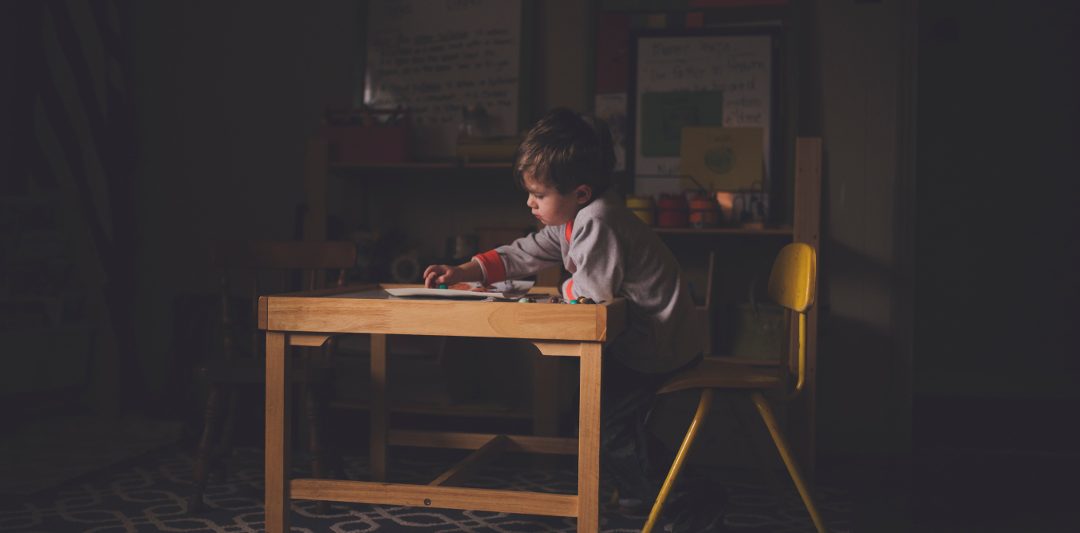 A child sitting alone at a desk.
